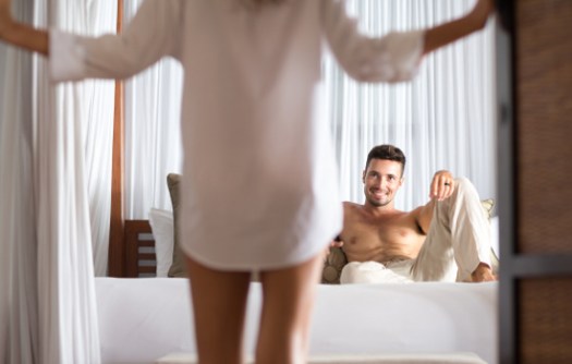 woman seduces her boyfriend in the bedroom, he lying on bed and looking at her